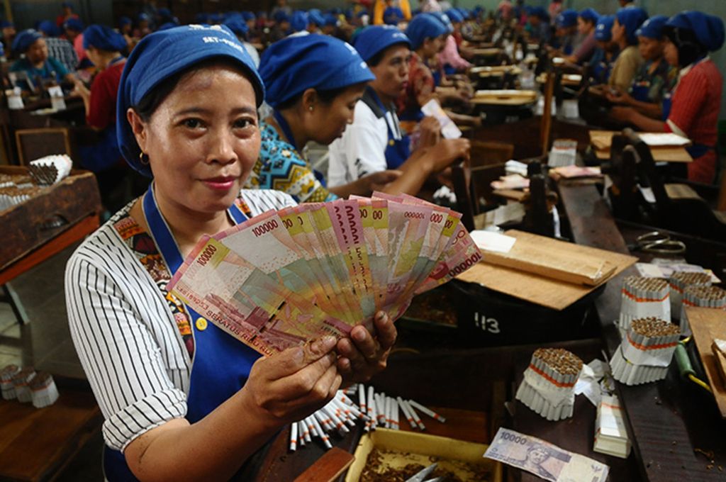 Pekerja pabrik menunjukkan uang tunjangan hari raya (THR) Lebaran di pabrik rokok, Kudus, Jawa Tengah, Selasa (5/6/2018). 