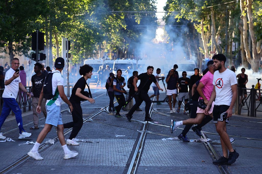 Para pengunjuk rasa lari dari tabung gas air mata yang dilemparkan polisi di Marseille, Perancis, Sabtu (1/7/2023). 