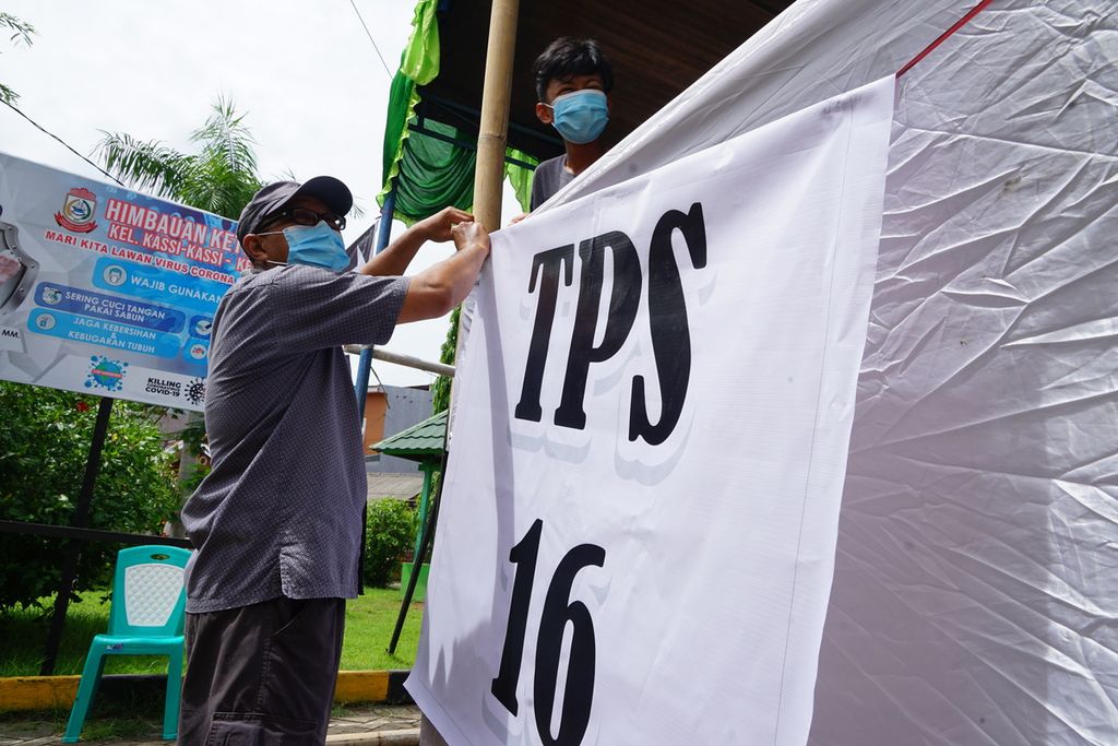 Petugas, dibantu warga, memasang tempat pemungutan suara (TPS), di Makassar, Sulawesi Selatan, Selasa (8/12/2020) siang. 