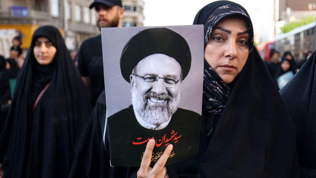 Pelayat di Teheran, Iran, pada Rabu (22/5/2024), membawa foto mendiang Presiden Iran Ebrahim Raisi.