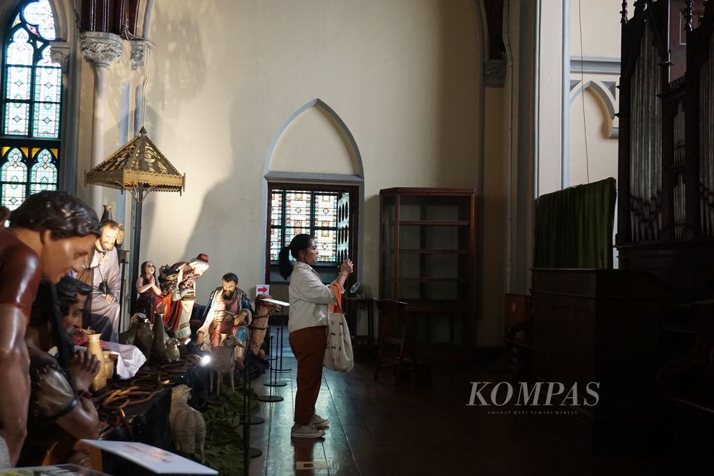 Pengunjung memotret orgel yang berhadapan dengan diorama kelahiran Yesus Kristus di mezanin Gereja Katedral Jakarta untuk menyambut perayaan Natal, Kamis (21/12/2023).