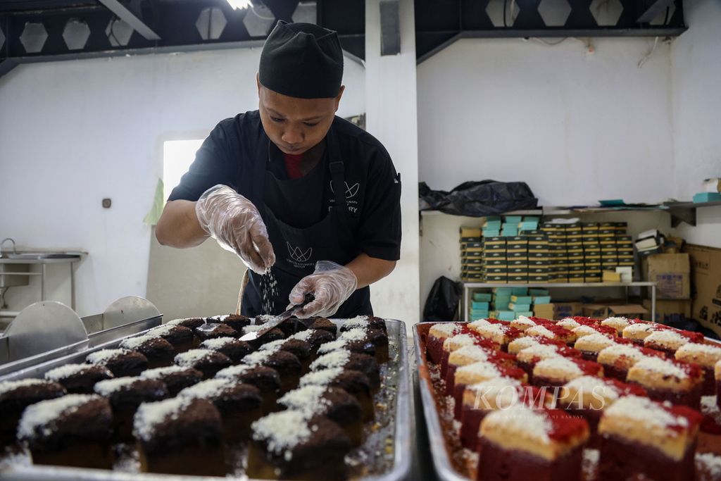 Pekerja menaburkan cokelat putih di atas cake di Minimolasnack, Penjaringan, Jakarta Utara, Senin (11/12/2023). Pemesanan hamper menjelang Natal mulai meningkat. Dalam sehari, mereka dapat mengirim 50-100 boks hamper berisi keik. Mereka menjual dua jenis keik berjenis red velvet ganache cake dan cokelat ganache cake. 
