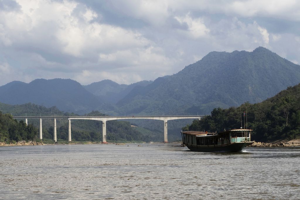 Sebuah perahu melintasi jembatan kereta cepat China yang dibangun di atas Sungai Mekong di utara kota Luang Prabang, Laos, 12 Desember 2023. Laos yang menjadi Ketua ASEAN 2024 mengusung tema "ASEAN: Enhancing Connectivity and Resilience".