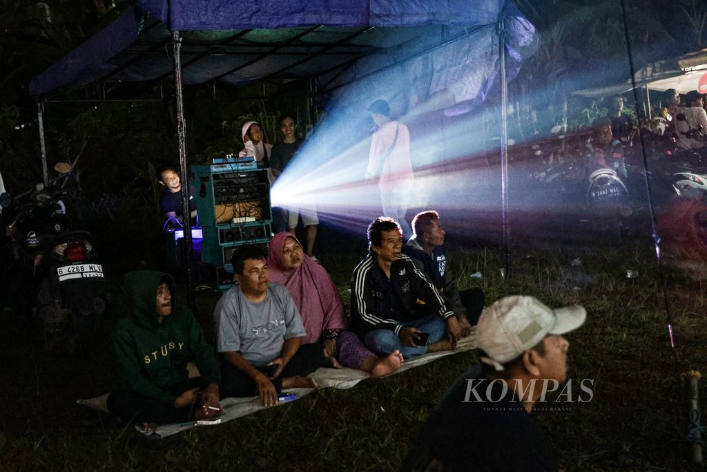 Antusiasme warga menyaksikan film yang diputar dalam festival layar tancap di Babakan, Kecamatan Setu, Tangerang Selatan, Banten, Rabu (18/1/2023) malam. 
