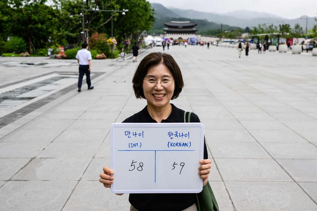 Dalam foto yang diambil pada 21 Juni 2023 ini, warga Korsel, Lee Jung-hee, memperlihatkan papan bertuliskan umur internasionalnya (58) dan umur Korea (59). 