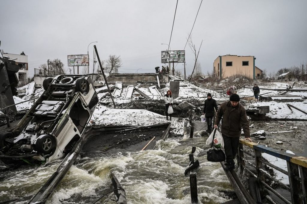 Warga sipil menyeberangi sungai  melalui jembatan yang telah diledakkan di front utara Kyiv pada 1 Maret 2022. Dalam perang Rusia di Ukraina, China bersikap lebih memihak pada langkah yang diambil Rusia.