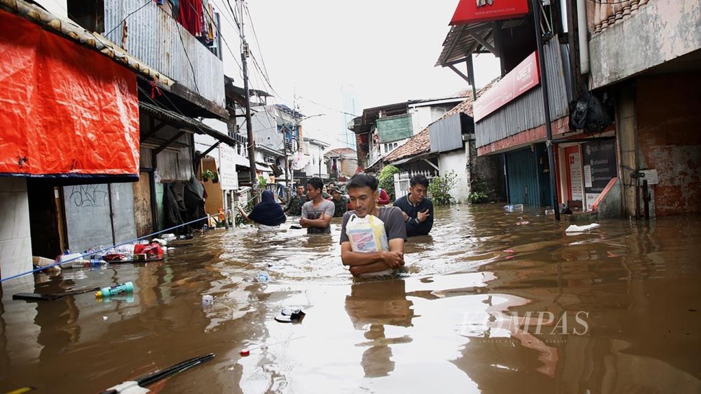 Warga menembus banjir akibat meluapnya Kali Krukut di Kelurahan Karet Tengsin, Tanah Abang, Jakarta Pusat, Selasa (25/2/2020). 