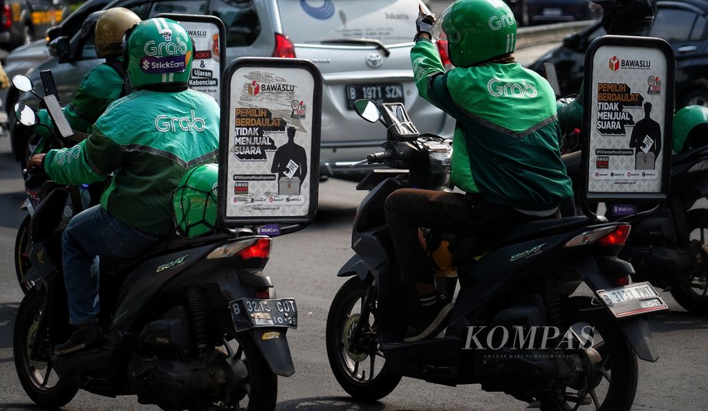 Sejumlah sepeda motor ojek <i>online</i> (ojol) dengan papan iklan layanan masyarakat Badan Pengawas Pemilu (Bawaslu) saat melintas di Bundaran Hotel Indonesia, Jakarta, Jumat (29/12/2023).