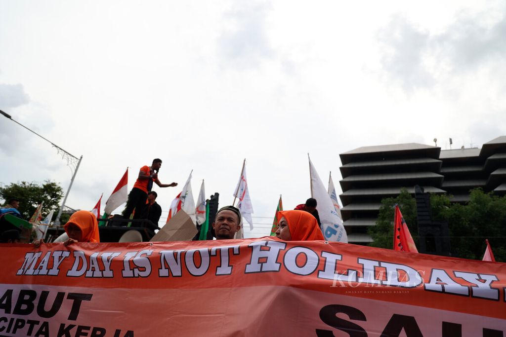 Aktivis dari perwakilan serikat pekerja membawa poster yang bertuliskan May Day is Not Holiday saat aksi unjuk rasa untuk memperingati Hari Buruh Internasional di depan Kantor DPRD Jawa Tengah, Kota Semarang, Senin (1/4/2023). 