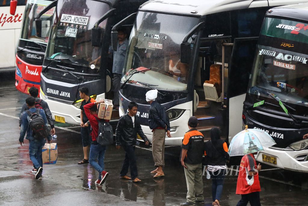 Ilustrasi: Penumpang menembus hujan menuju bus di Terminal Kampung Rambutan, Jakarta Timur, Minggu (22/12/2019).