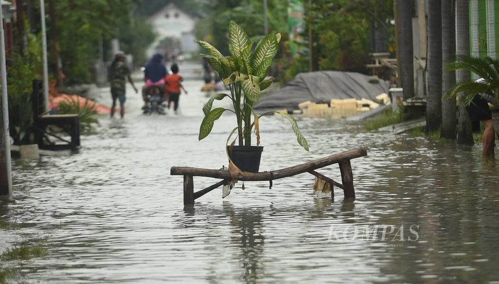 Sebuah pot bunga diletakkan di tengah jalan yang banjir akibat luapan Kali Lamong di Kecamatan Benjeng, Kabupaten Gresik, Jumat (11/2/2022). 