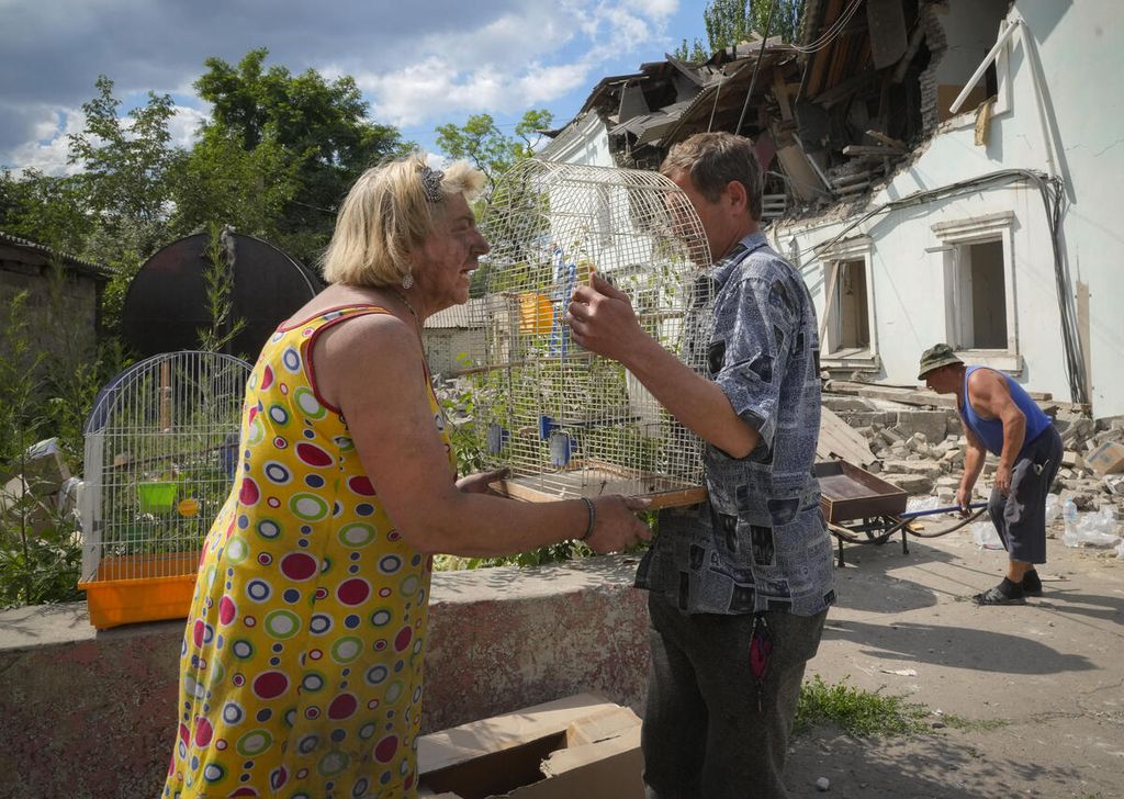 Seorang wanita bereaksi setelah seekor burung beo miliknya yang masih hidup di dalam kandang dapat diselamatkan dari bawah reruntuhan gedung setelah terjadinya serangan udara Rusia di Lysychansk, wilayah Luhansk, Ukraina, Kamis (16/6/2022). 