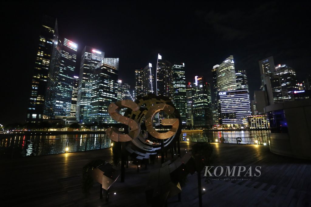 Seorang warga menikmati pemandangan malam di sekitar Hotel Marina Bay Sands di Bayfront Ave, Singapura, Rabu (5/7/2023). Kawasan yang dibangun di atas lahan reklamasi ini sekarang telah berkembang pesat dan menjadi tujuan wisata populer Singapura.