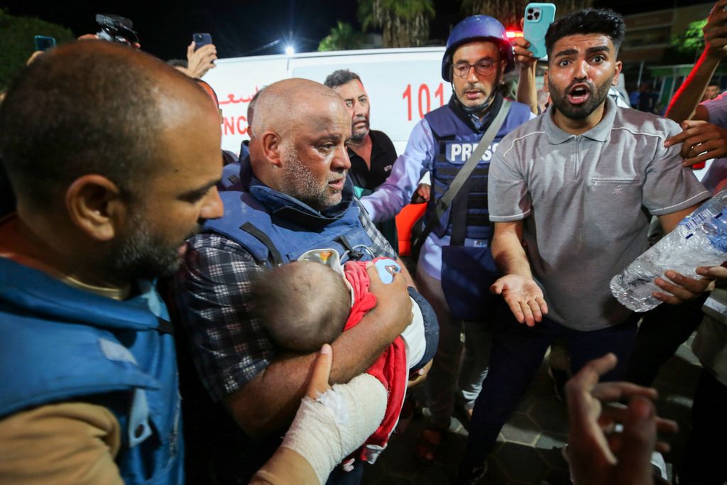 Jurnalis Al Jazeera di Gaza, Wael Dahdouh, menggendong jenazah salah satu dari tiga anaknya yang tewas akibat serangan udara Israel di Nuseirat, Gaza, Rabu (25/10/2023). Ia kehilangan istri dan tiga anaknya dalam serangan itu