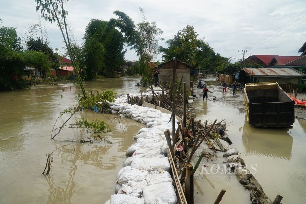 Karung berisi pasir menjadi tanggul darurat untuk menahan luapan air Batang Merao yang memicu banjir di Desa Tanjung, Kecamatan Hamparan Rawang, Kota Sungai Penuh, Jambi, Sabtu (20/1/2024).
