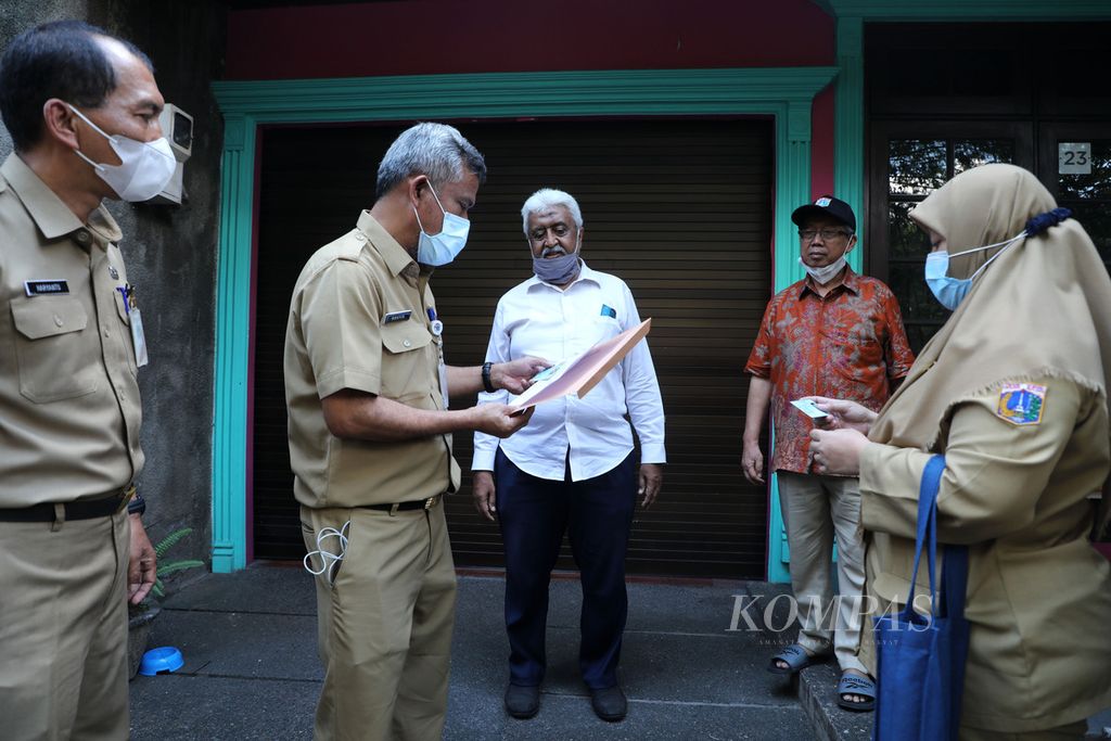 Petugas Dinas Kependudukan dan Pencatatan Sipil DKI Jakarta menyerahkan KTP dengan alamat baru kepada warga di Jalan Raden Ismail, Cideng, Jakarta Pusat, Senin (4/7/2022). 
