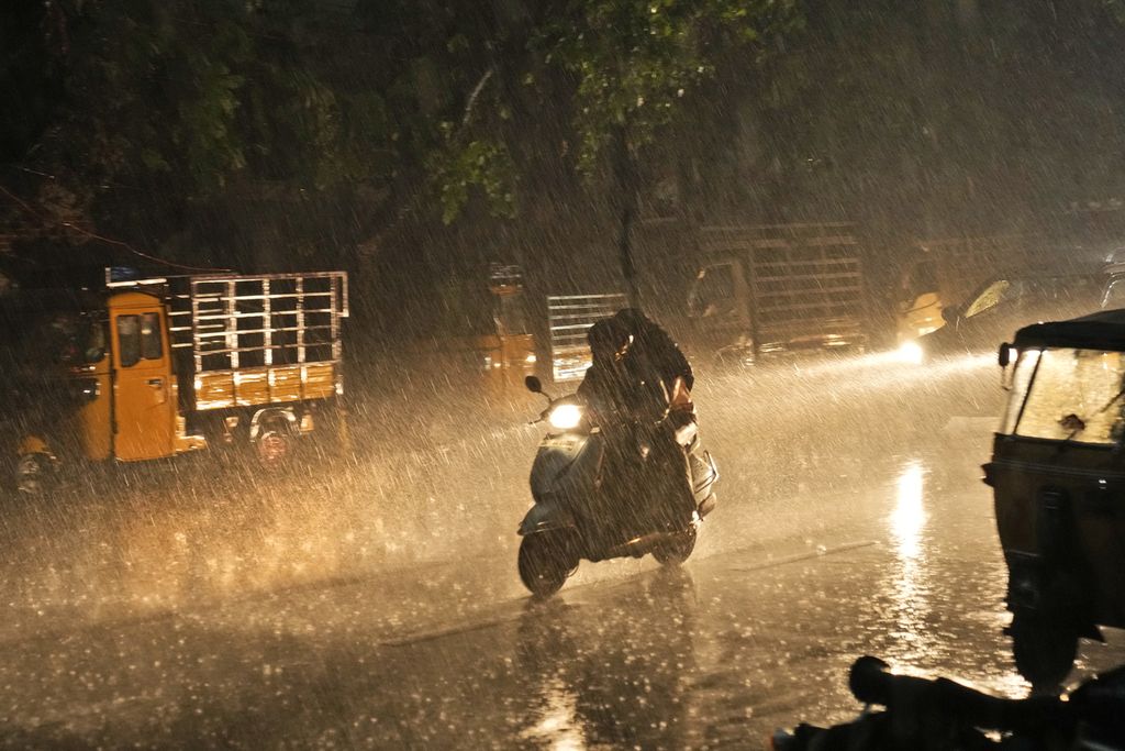 Pengendara sepeda motor menembus hujan lebat di Hyderabad, India, 7 Mei 2024. 