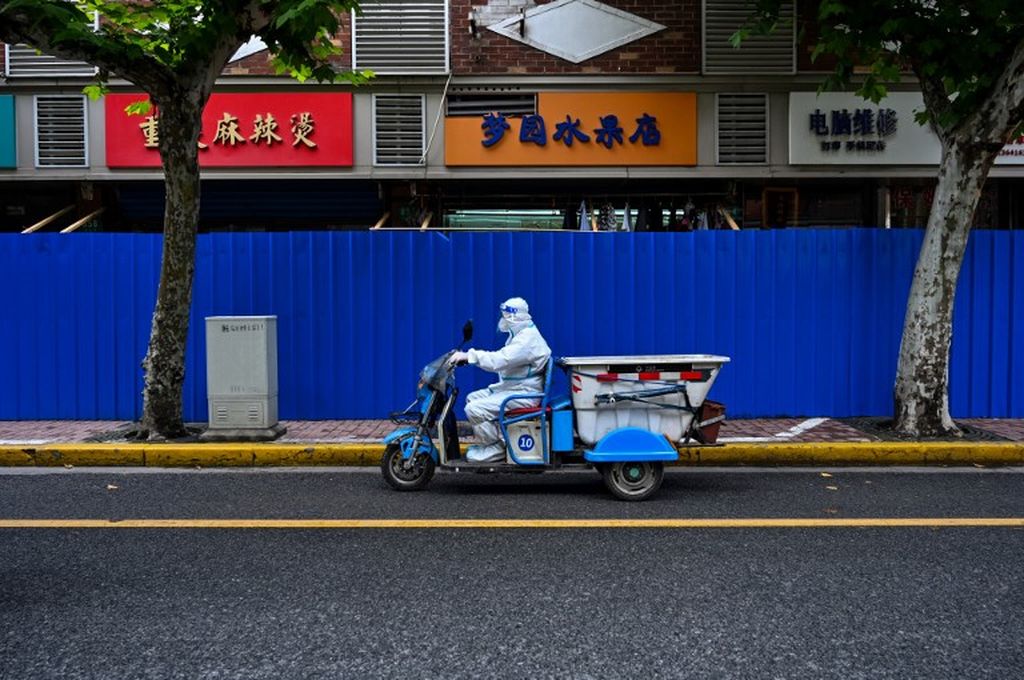 Tenaga kesehatan dengan alat pelindung diri mengendarai kendaraan bermotor di jalan saat pemberlakuan karantina wilayah untuk mencegah penyebaran Covid-19 di Distrik Jing'an, Shanghai, China, 29 Mei 2022. 