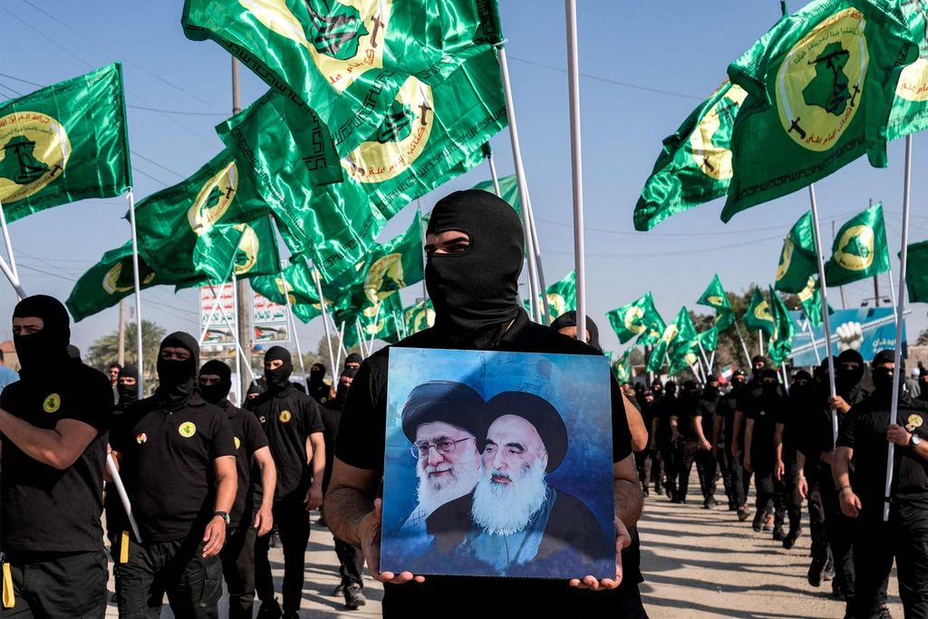 Seorang anggota Batalion Imam Ali, sayap militer Gerakan Islam di Irak, anggota faksi Pasukan Mobilisasi Rakyat, memegang foto pemimpin revolusi Iran Ayatollah Ruhollah Khomeini (kanan) dan Pemimpin Tertinggi Iran Ali Khamenei dalam pawai perayaan Hari Quds (Jerusalem) di Baghdad, Irak, 5 April 2024. 