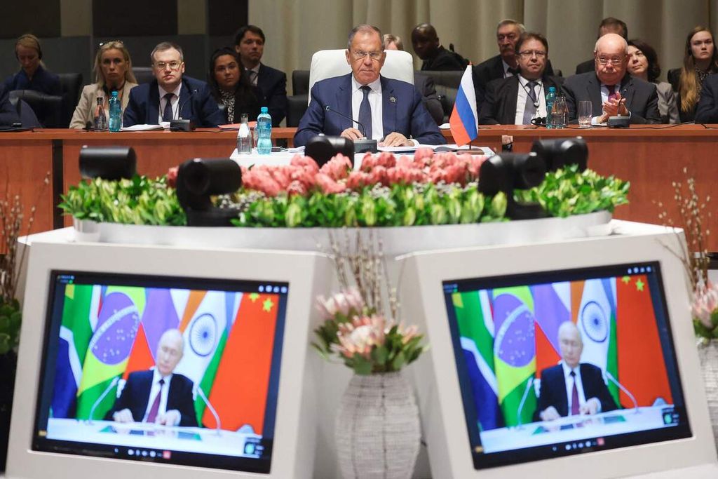 Menteri Luar Negeru Rusia Sergey Lavrov (tengah) mendengarkan saat Presiden Rusia Vladimir Putin (dalam layar) menyampaikan pidato sambutan dalam KTT BRICS di Johannesburg, Afrika Selatan, Rabu (23/8/2023). 