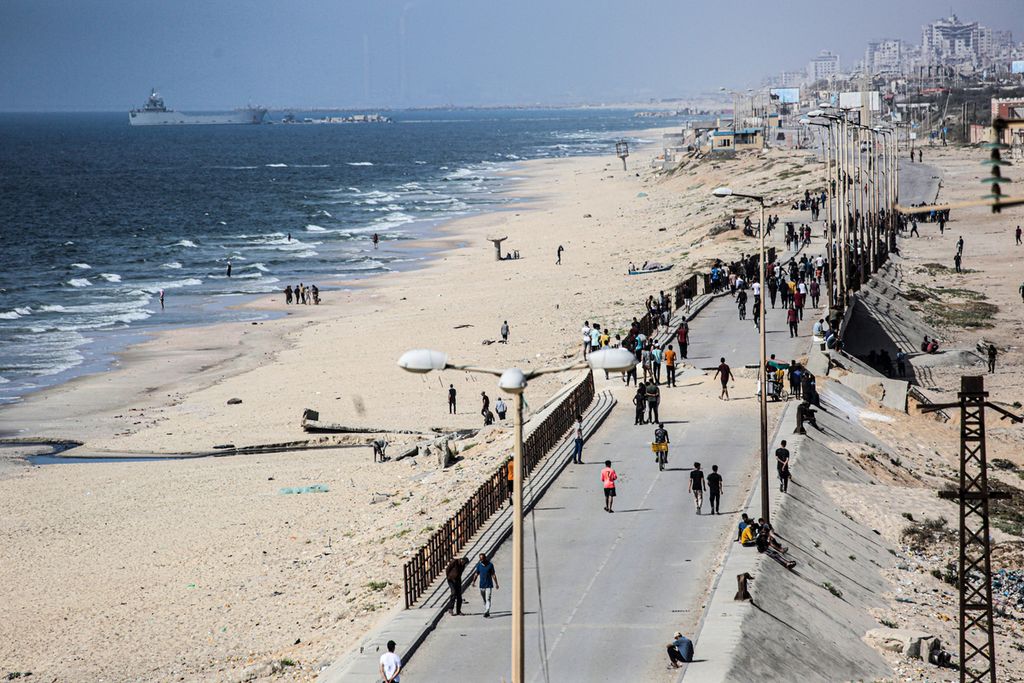 A ship carrying international humanitarian aid was docked at the Trident Wharf built by the US while Palestinian residents walked along the main road near Nuseirat in the Gaza Strip on May 21, 2024.