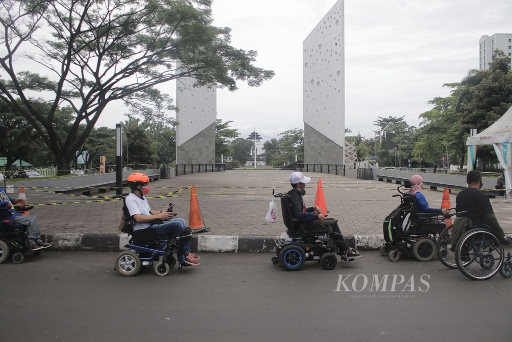 Sejumlah pengguna kursi roda melintasi Jalan Wirayuda Barat, dekat Monumen Perjuangan Covid-19, Kota Bandung, Jawa Barat, Selasa (1/3/2022). Mereka melintasi sejumlah jalan di Kota Bandung untuk memperingati Hari Kursi Roda Internasional.