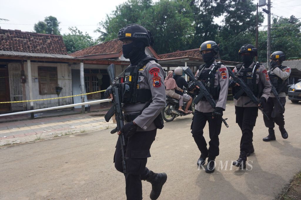 Sejumlah aparat melintas di depan rumah yang diberi garis polisi, Rabu (15/6/2022), di Desa Randegan, Kebasen, Banyumas, Jawa Tengah.