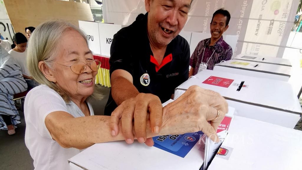 Seorang lansia, Dien (83) dibantu anaknya memasukkan kertas suara yang sudah dicoblos usai mengunakan hak pilihnya di TPS 073, Rw 04 Kelurahan Joglo, Kembangan, Jakarta, Rabu (17/4/2019). Tua muda tak terkecuali menunjukkan antusiasme mengikuti Pemilu 2019.