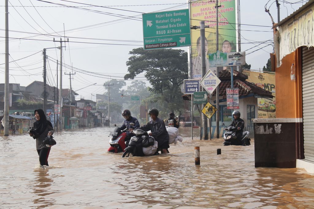 Sejumlah pemuda mendorong kendaraan roda dua saat melintasi Jalan Raya Baleendah, Kabupaten Bandung, Jawa Barat, yang tergenang banjir setinggi lebih dari 1 meter, Rabu (18/12/2019)