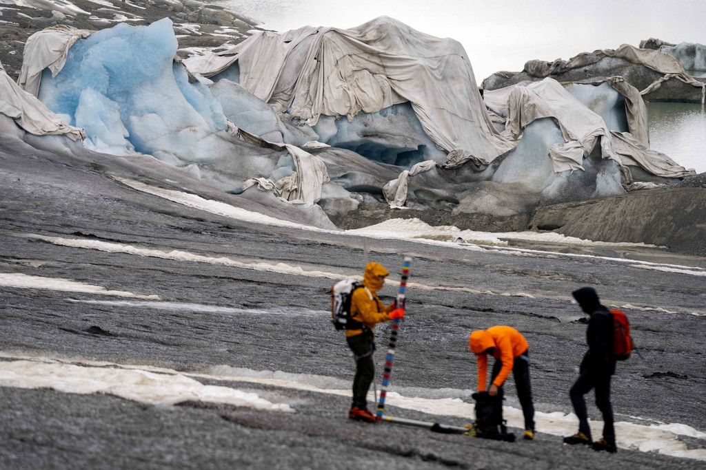 Foto yang diambil pada 16 Juni 2023 memperlihatkan sejumlah peneliti gletser dari Institut Teknologi Federal Swiss tengah melakukan peninjauan di Gletser Rhome di Grom, Swiss. Hasil laporan GLOMS menyebut Swiss telah kehilangan 10 persen volume gletsernya hanya dalam waktu dua tahun. 