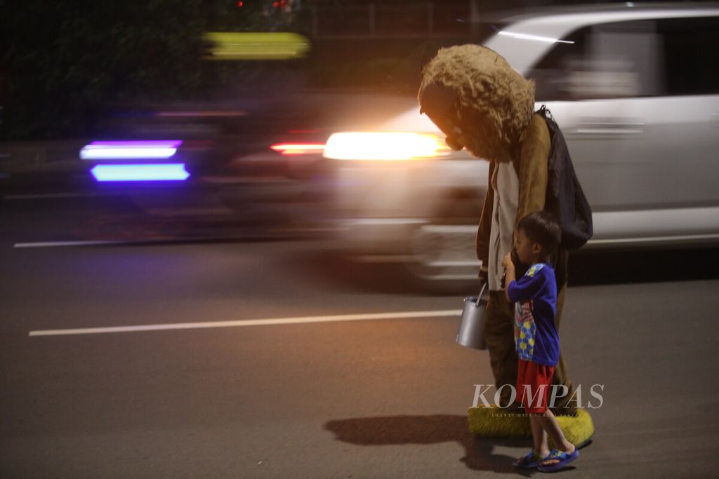 Pengamen beratribut baju badut menggandeng seorang bocah berkelana di jalanan Kalimalang, Duren Sawit, Jakarta Timur, Selasa (21/6/2022). Menjadi badut jalanan di Ibu Kota madi pilihan bagi sebagian orang untuk menopang hidup mereka sehari-hari. 