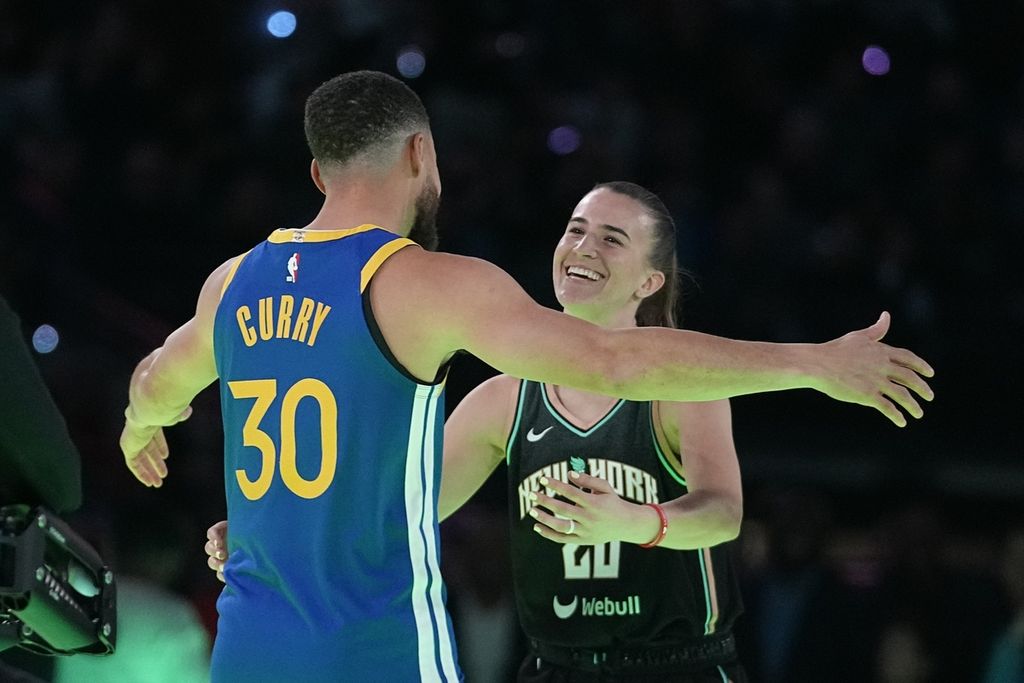 <i>Guard</i> Golden State Warriors, Stephen Curry, memeluk <i>guard</i> New York Liberty, Sabrina Ionescu, setelah kontes tiga angka dalam acara NBA All-Star, Minggu (18/2/2024) dini hari WIB. 