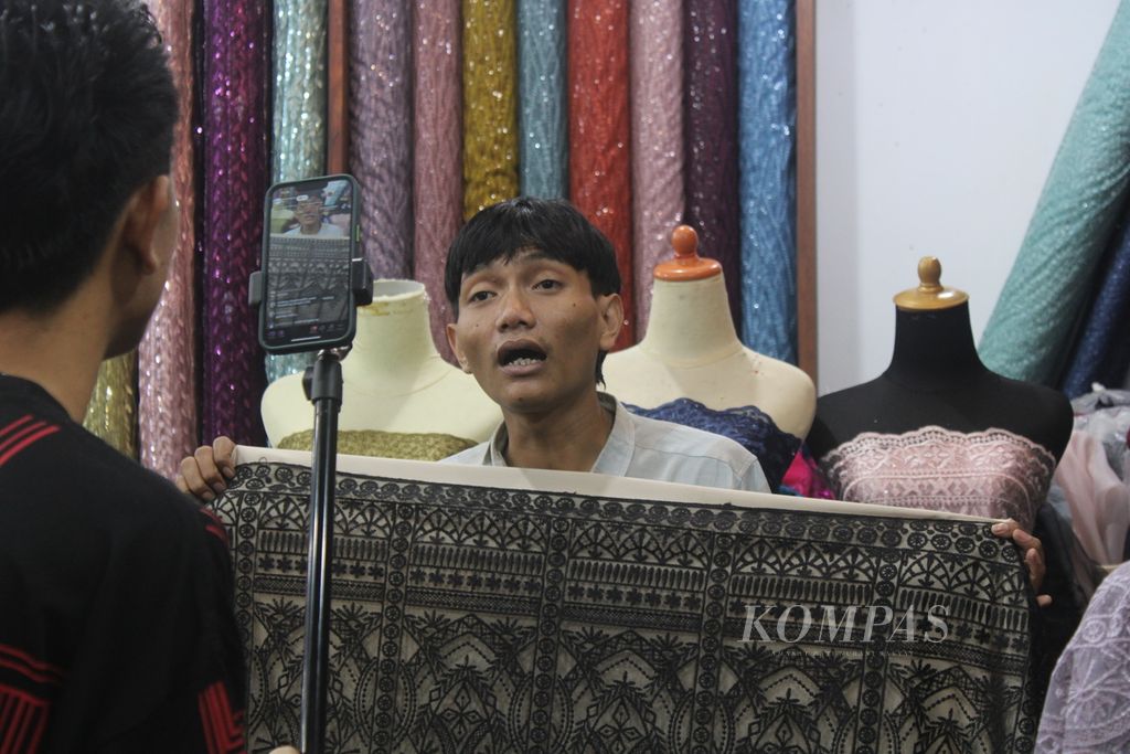 Salah satu pegawai toko di Kawasan Tekstil Cigondewah, Kota Bandung, Jawa Barat, menyiarkan langsung salah satu produk yang dia jual di salah satu media sosial, Kamis (29/2/2024).