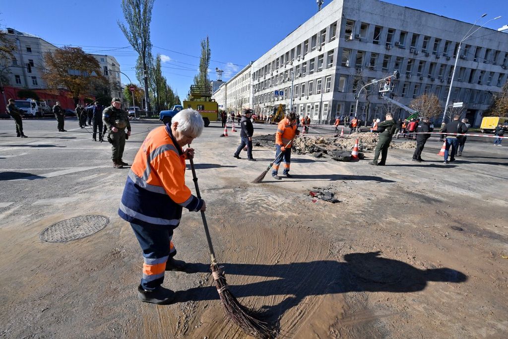 Petugas kebersihan kota Kyiv membersihkan sisa-sisa serangan rudal Rusia di sebuah lokasi di ibu kota Ukraina itu, Senin (10/10/2022). 