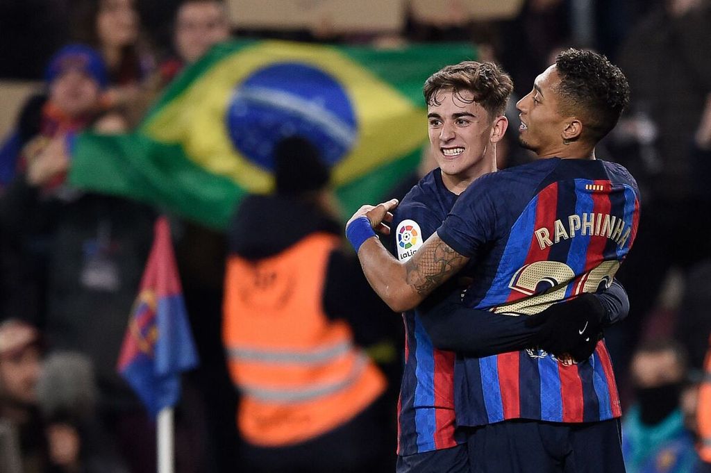 Penyerang Barcelona, Raphinha (kanan), memeluk rekan setimnya, Gavi, seusai mencetak gol ke gawang Sevilla pada laga Liga Spanyol di Stadion Camp Nou, Barcelona, Senin (6/2/2023) dini hari WIB. Barca menang, 3-0.