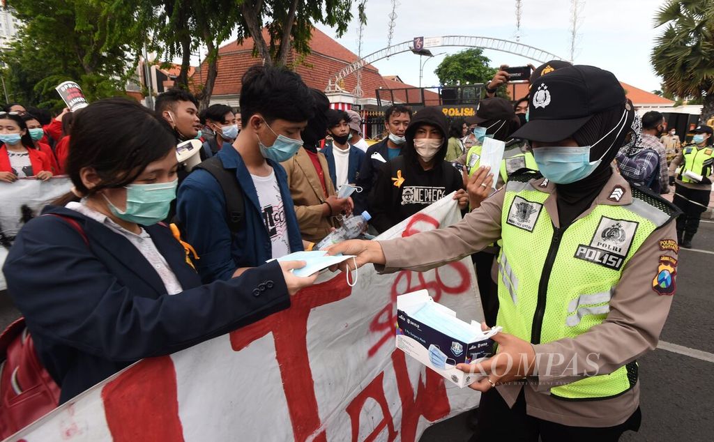 Polwan membagikan masker saat berlangsung unjuk rasa menolak Omnibus Law di Gedung Grahadi, Surabaya, Jawa Timur (20/10/2020). 