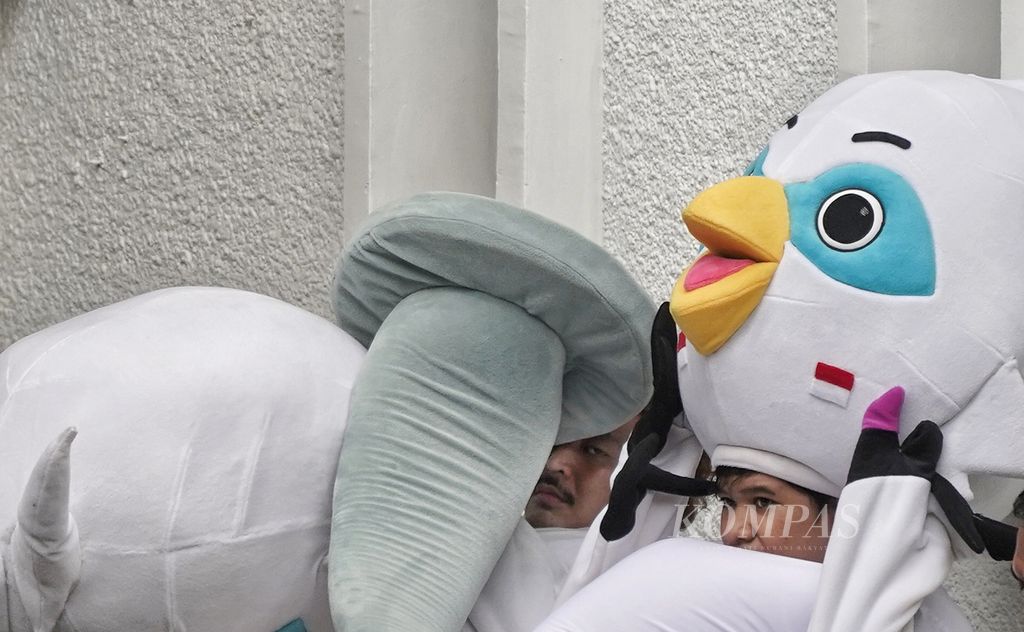Petugas dengan mengenakan kostum boneka maskot Pemilu 2024 Sura dan Sulu beristirahat dan mengusir rasa gerah setelah beraksi pada acara Deklarasi Kampanye Pemilu Damai Tahun 2024 di halaman Kantor Komisi Pemilihan Umum, Jakarta, Senin (27/11/2023).