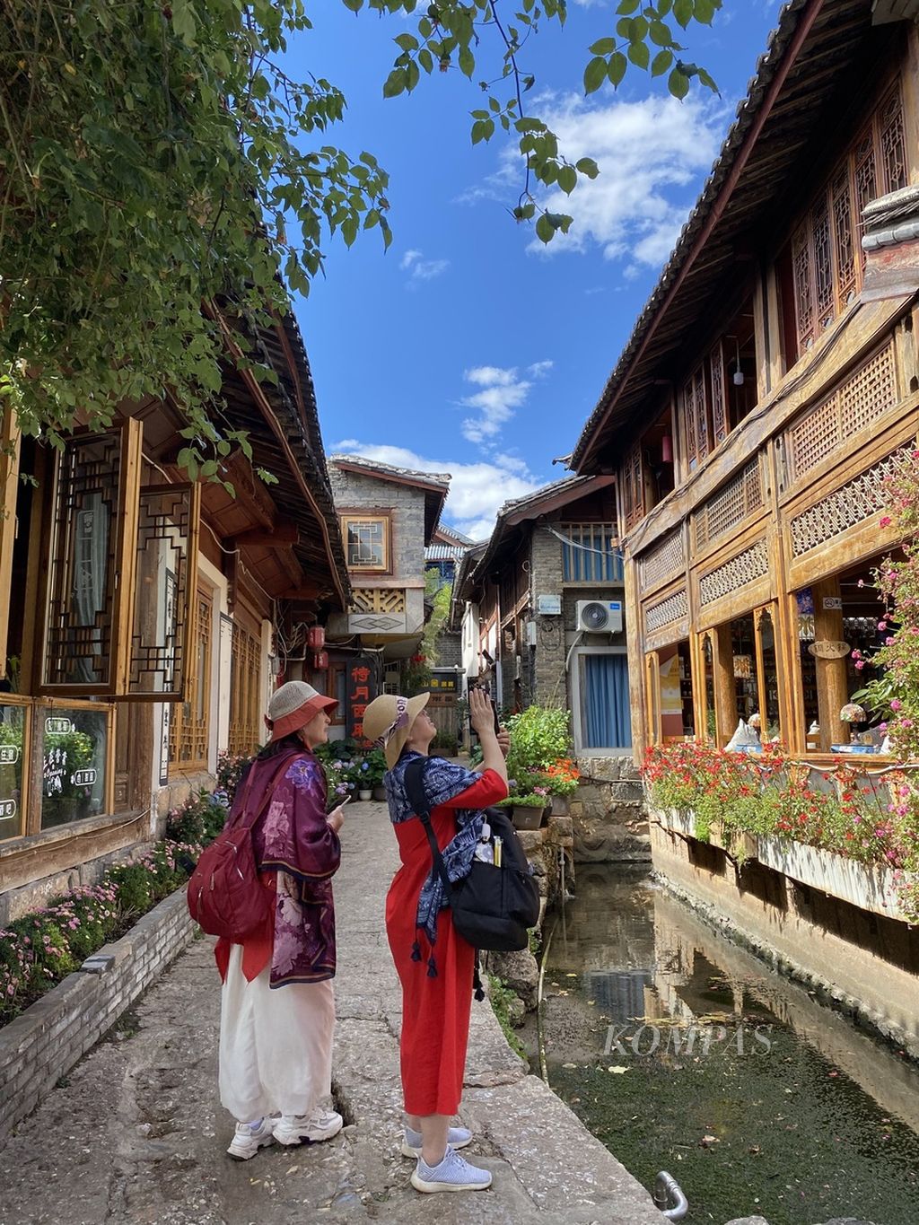 Wisatawan mengamati detail arsitektur kuno di kawasan kota tua Lijiang, China.