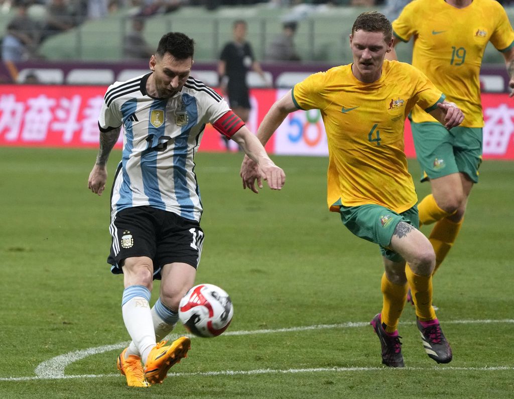 Bintang Argentina, Lionel Messi (kiri), menendang bola melewati pemain Australia, Kye Rowles, pada laga uji coba di Stadion Pekerja, Beijing, China, Kamis (15/6/2023). Argentina mengalahkan Australia, 2-0.