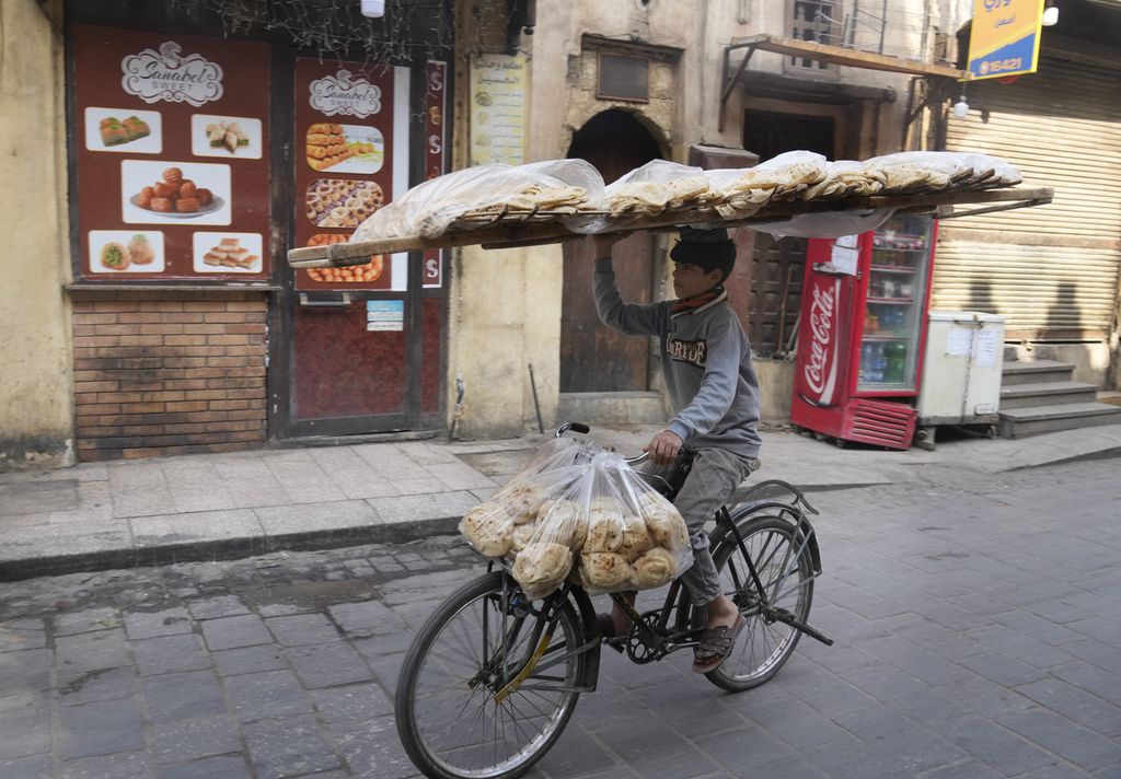 Seorang pedagang mengendarai sepeda sambil membawa roti tradisional Mesir, baladi, di Distrik Kairo Lama, Mesir, 22 Maret 2022.