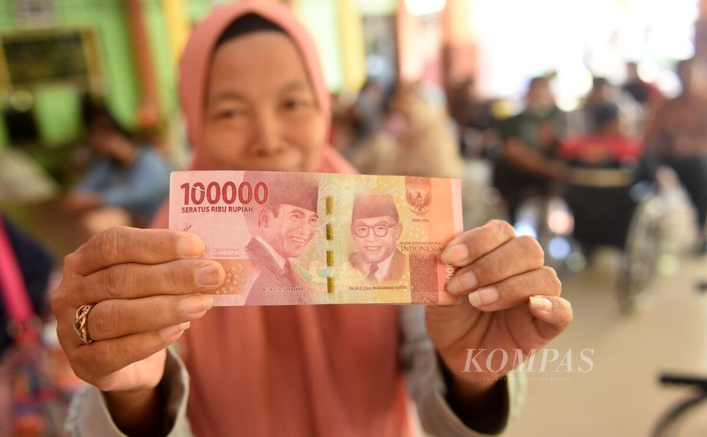 Warga menunjukkan uang yang diterimanya saat pencairan bantuan sosial penyandang disabilitas berat di pendopo Kantor Kecamatan Waru, Kabupaten Sidoarjo, Jawa Timur, Kamis (15/9/2022). 