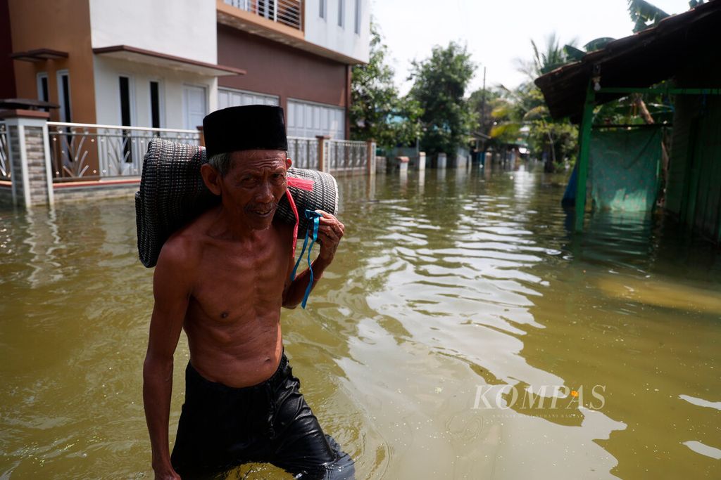 Ilustrasi. Warga melintasi genangan banjir di Desa Wonoketingal, Kecamatan Karangtengah, Kabupaten Demak, Jawa Tengah, Kamis (15/2/2024). 
