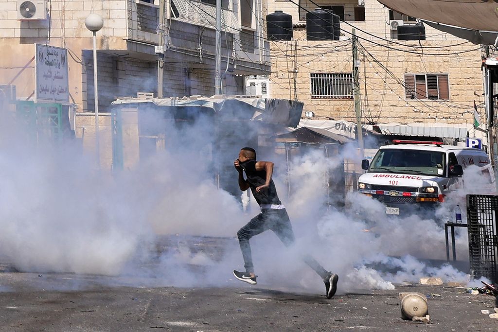 Seorang pria mencoba menghindar dari tembakan peluru tajam dan serangan gas air mata dari militer Israel yang melakukan operasi militer ke Jenin, kota di Tepi Barat, Selasa (4/7/2023). 