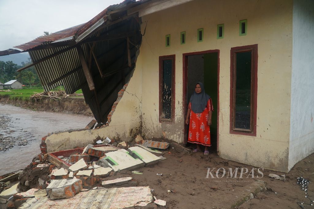 Raminis (43), warga terdampak banjir bandang, berdiri di rumahnya yang hancur akibat banjir bandang di Kampung Batu Bala, Nagari Ganting Mudik Utara Surantih, Kecamatan Sutera, Kabupaten Pesisir Selatan, Sumatera Barat, Selasa (12/3/2024). 