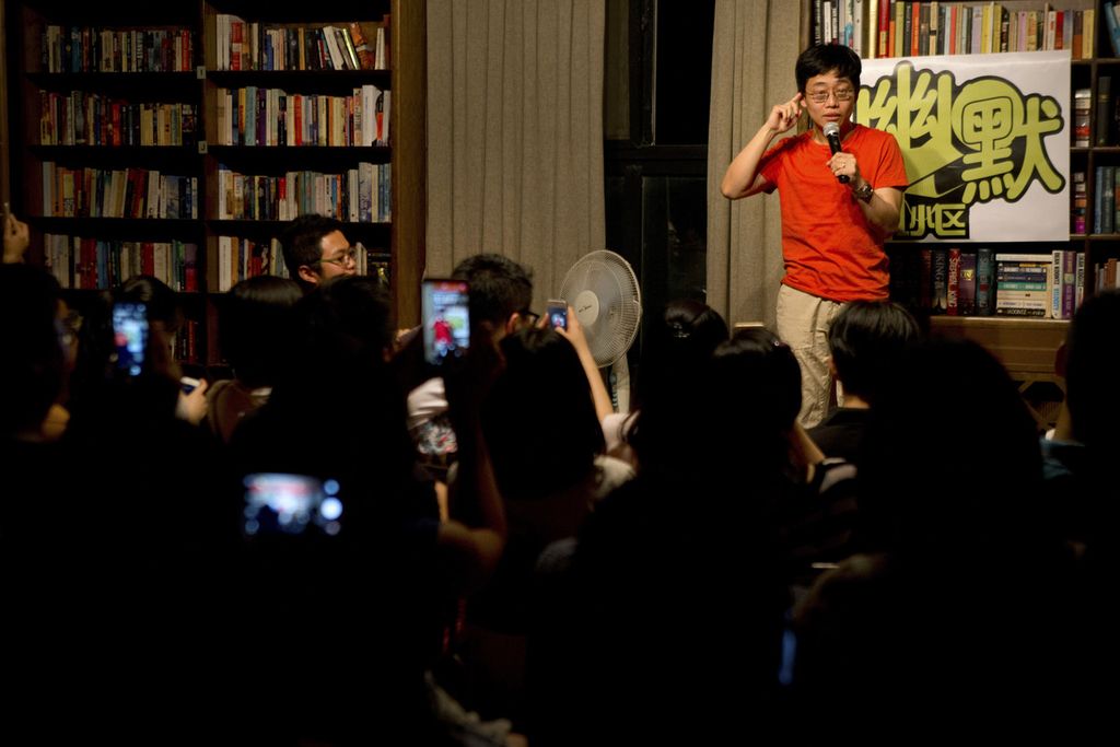 Dalam foto bertanggal 24 Mei 2015 ini, penonton mengambil foto saat komedian keturunan China-Amerika, Joe Wong, tampil dalam pertunjukan komedi di sebuah toko buku di Beijing, China. 