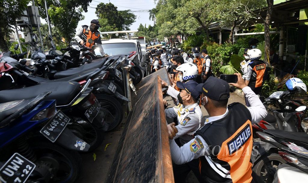 Petugas Suku Dinas Perhubungan menutup bak truk yang membawa kendaraan yang terkena razia penertiban parkir liar kendaraan di kawasan Senen, Jakarta Pusat, Rabu (2/6/2021). D