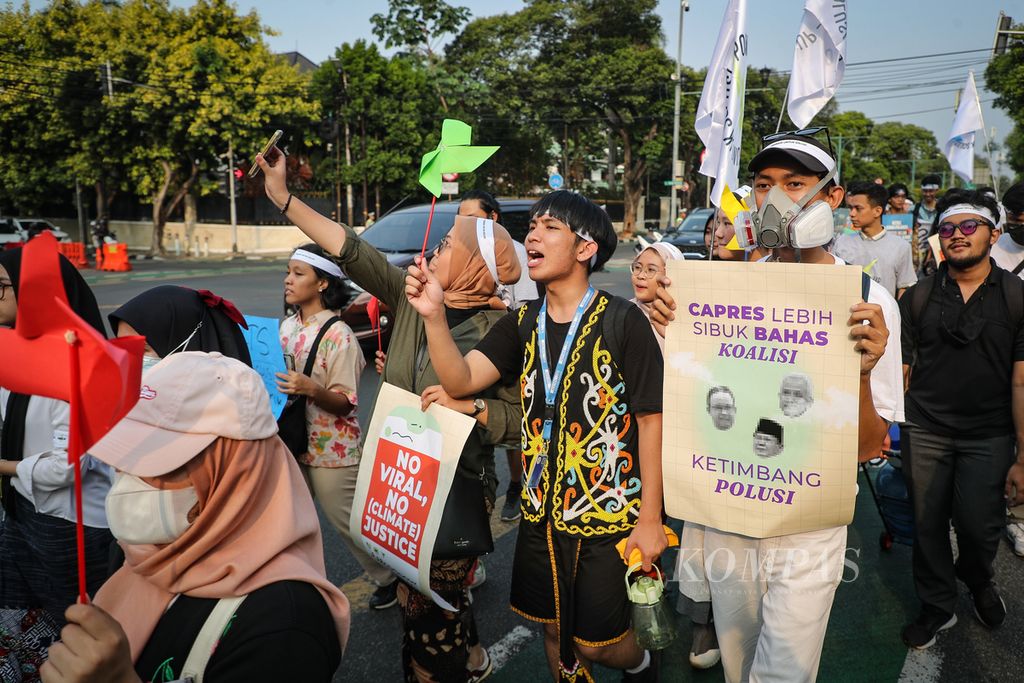 Peserta aksi "Power Up" berjalan sembari membawa poster kritik di Jalan Imam Bonjol, Jakarta, Jumat (3/11/2023). Aksi "Power Up" mendesak tiga calon presiden (capres) untuk mendeklarasikan komitmen yang kuat dalam penanganan krisis iklim dan transisi energi. 