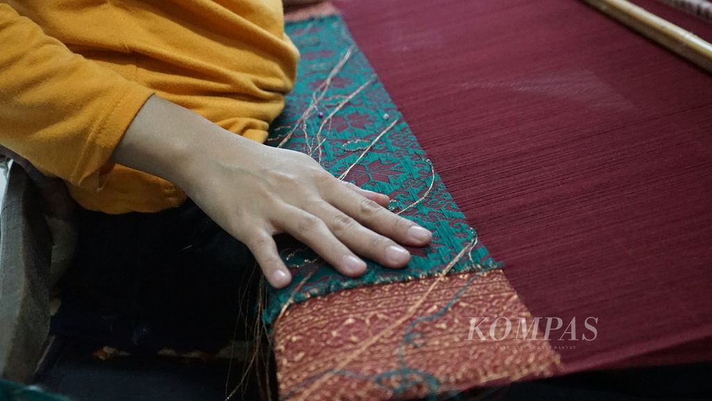 Proses penenunan kain songket di galeri Zainal Songket yang berlokasi di Jalan Ki Gede Ing Suro, Lorong Kuala Batu, 32 Ilir, Ilir Barat II, Palembang, Sumatera Selatan, Jumat (18/2/2022). Songket merupakan budaya turun-temurun dan menjadi ciri khas Kota Palembang.