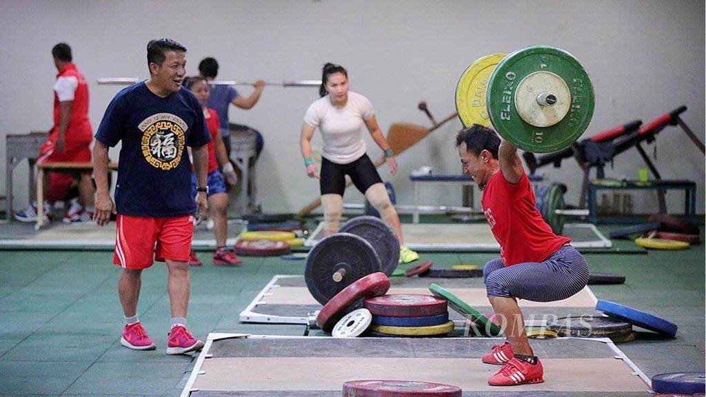 Pelatih angkat besi Indonesia, Dirdja Wiharja (kiri), mengawasi latihan lifter di Olympic Center, Cibubur, Jakarta Timur, Rabu (11/1). 