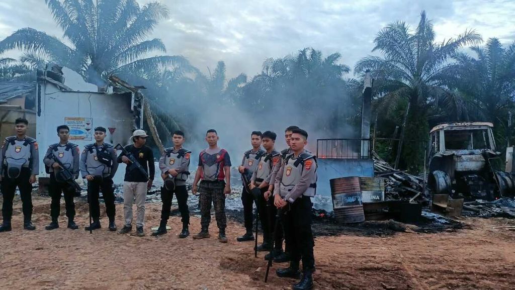 Polisi berjaga di dekat pabrik sawit yang dibakar sekelompok orang di Kabupaten Way Kanan, Lampung, Senin (30/1/2023). Pembakaran dipicu kemarahan warga sekitar setelah seorang warga tewas ditembak polisi karena diduga mencuri sawit. 